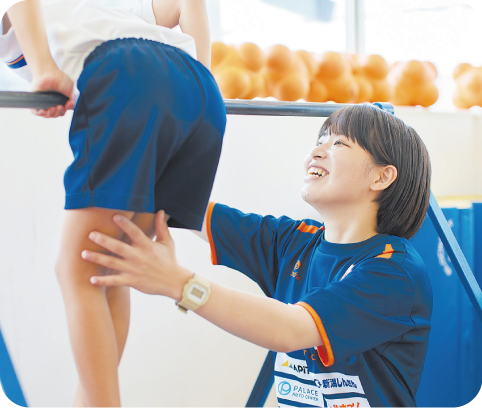 鉄棒する生徒を支える先生